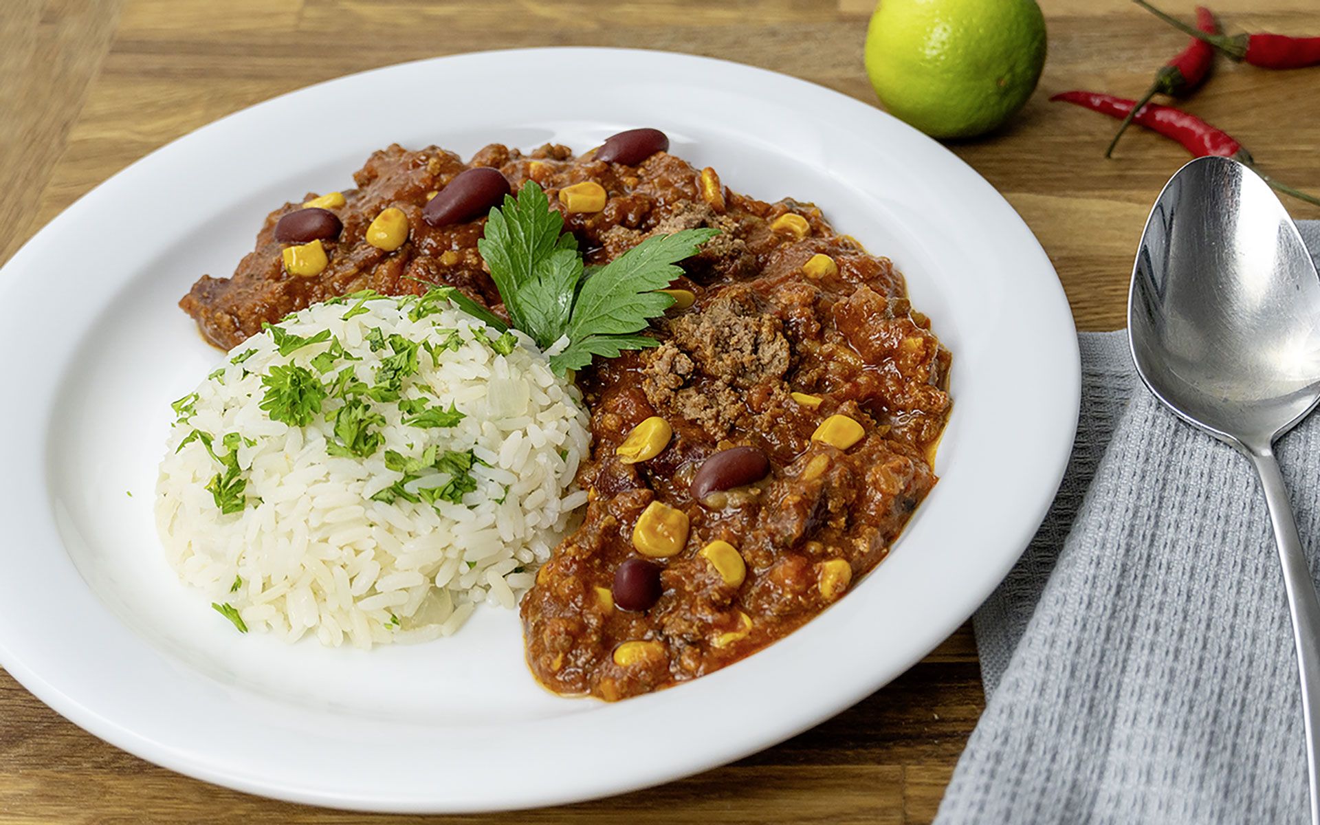 Foto eines unserer Speisen: Teller mit Chili con Carne, Reis, garniert mit frischen Kräutern